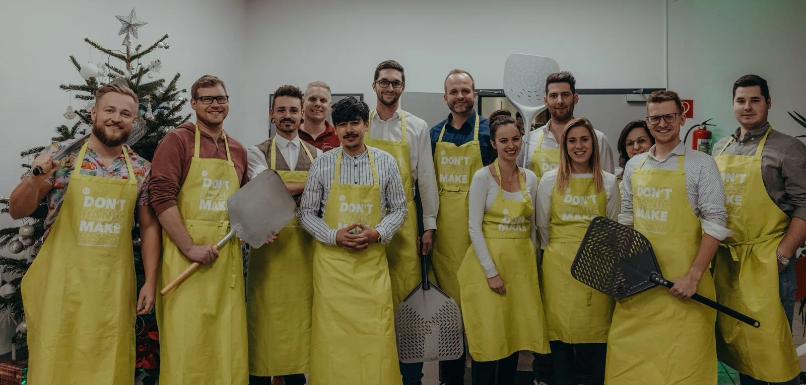The QMedia IT team in yellow aprons making pizza together