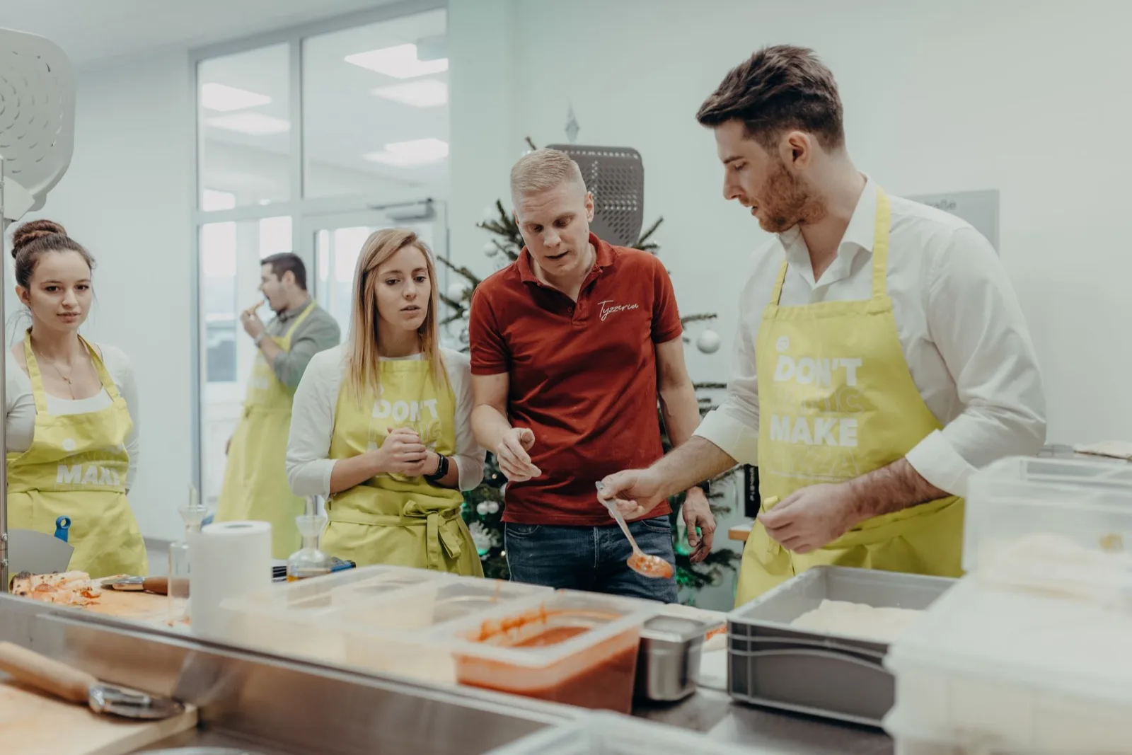 Colleagues in aprons topping pizzas together